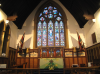 The Sanctuary today, showing the great East Window; the Altar with its painted panels; the Chaplain’s Memorial; and the First World War flags.